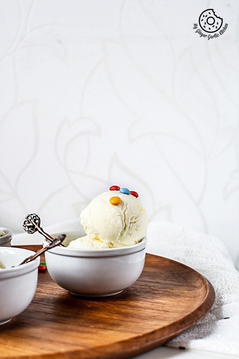 a bowl of homemade vanilla ice cream on a wooden tray