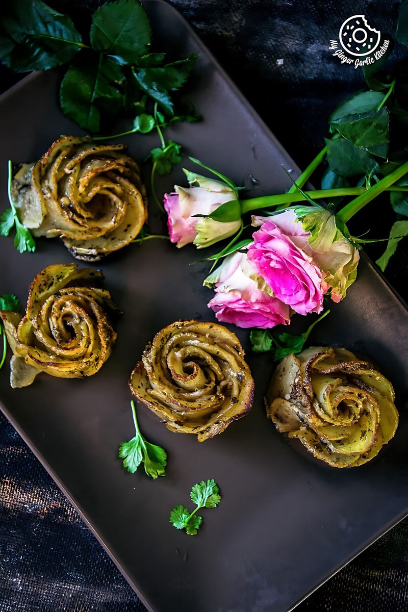 four potato roses or potato gratins on a plate with a black background