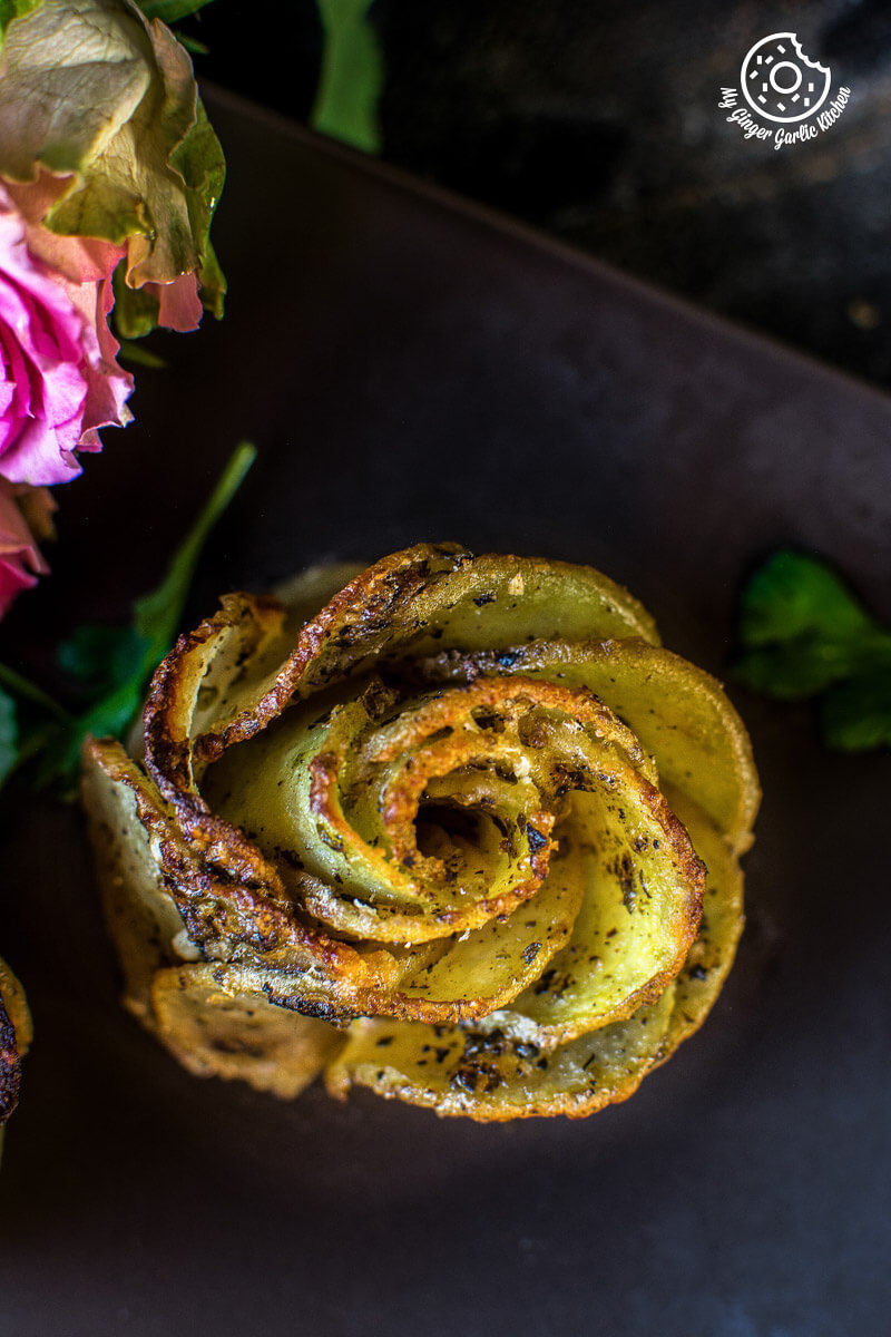 a potato rose or potato gratin that is sitting on a plate with some flowers