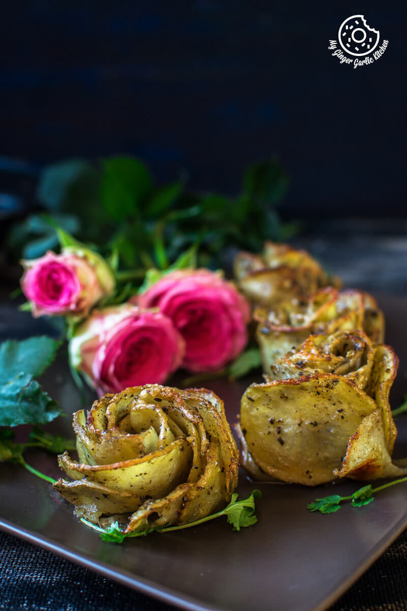 three potato roses aka potato gratins on a plate with a black background