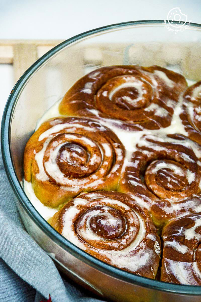 pumpkin cinnamon rolls in a glass dish with icing on a table