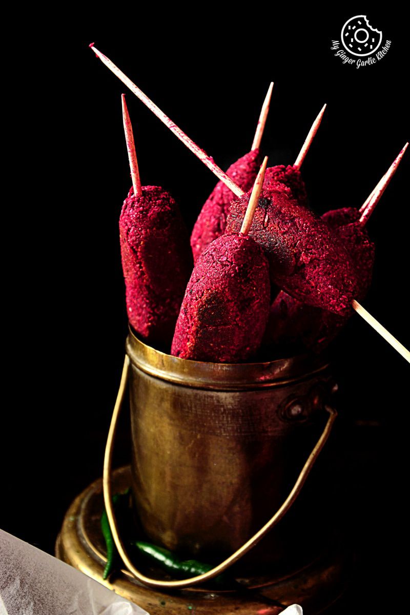 there are four red roasted beet kebabs in a brass bucket