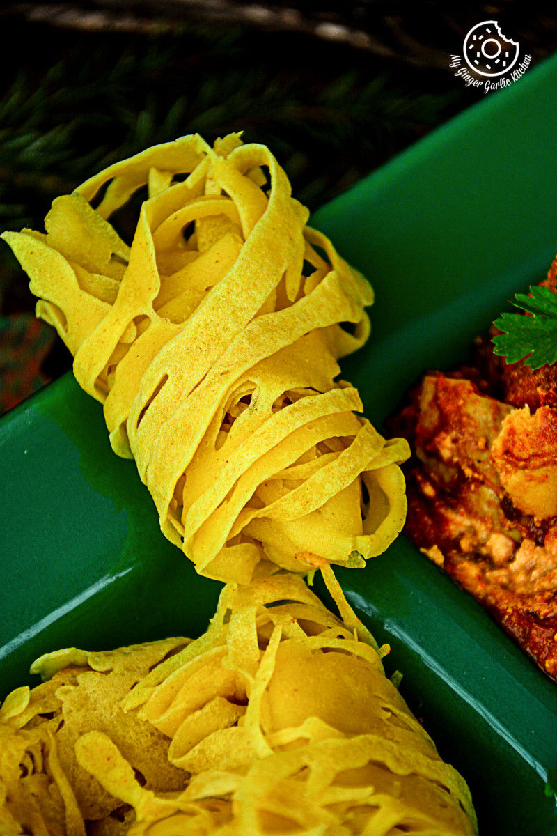 two green trays with roti jala and curry in them