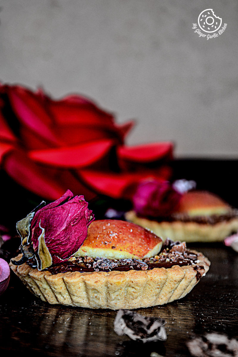 two snickers chocolate mini tarts with a rose on top of them