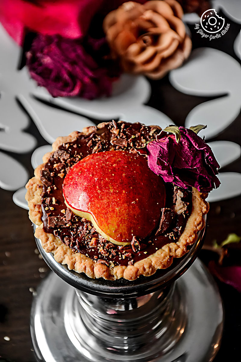 a snickers chocolate mini tart with a red apple on top of it