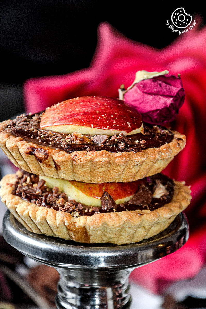 a stack of two snickers chocolate mini tarts with a rose in the background