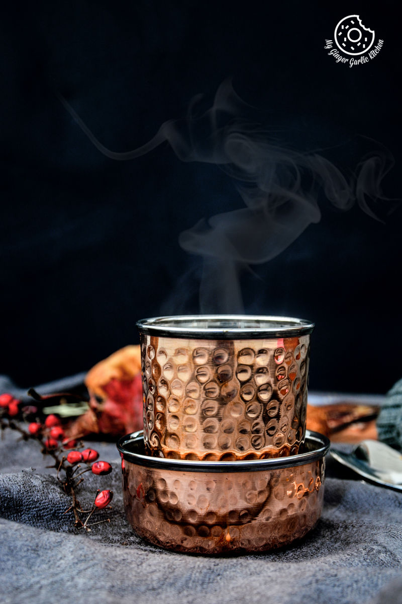 there is a copper pot of spiced kesar chai with a steam coming out of it