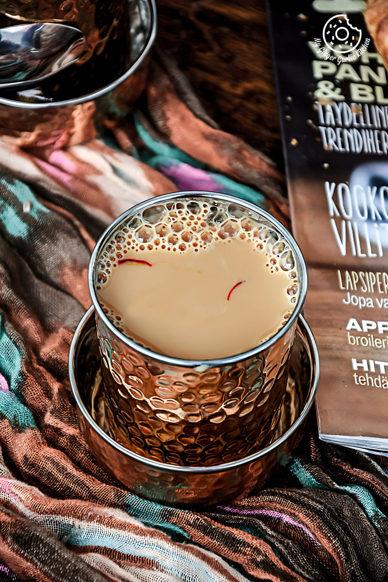 there is a cup of spiced kesar chai and a book on a blanket