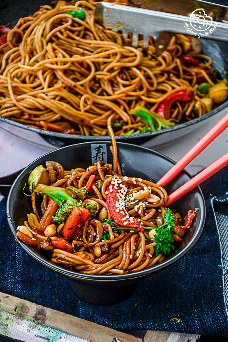 asian vegetable teriyaki noodles in a bowl with chopsticks and a bowl of noodles