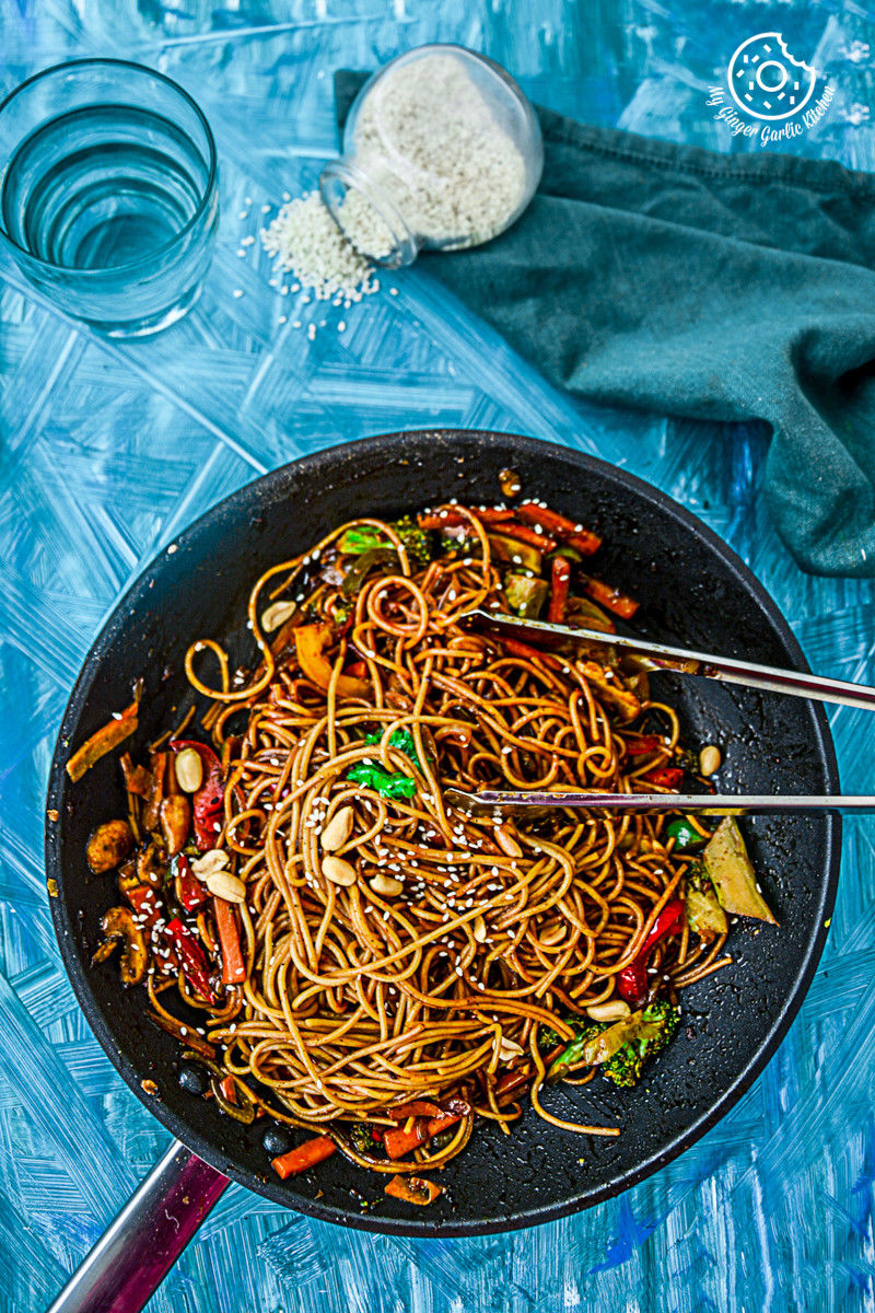 asian noodles in a wok with chopsticks on a blue table