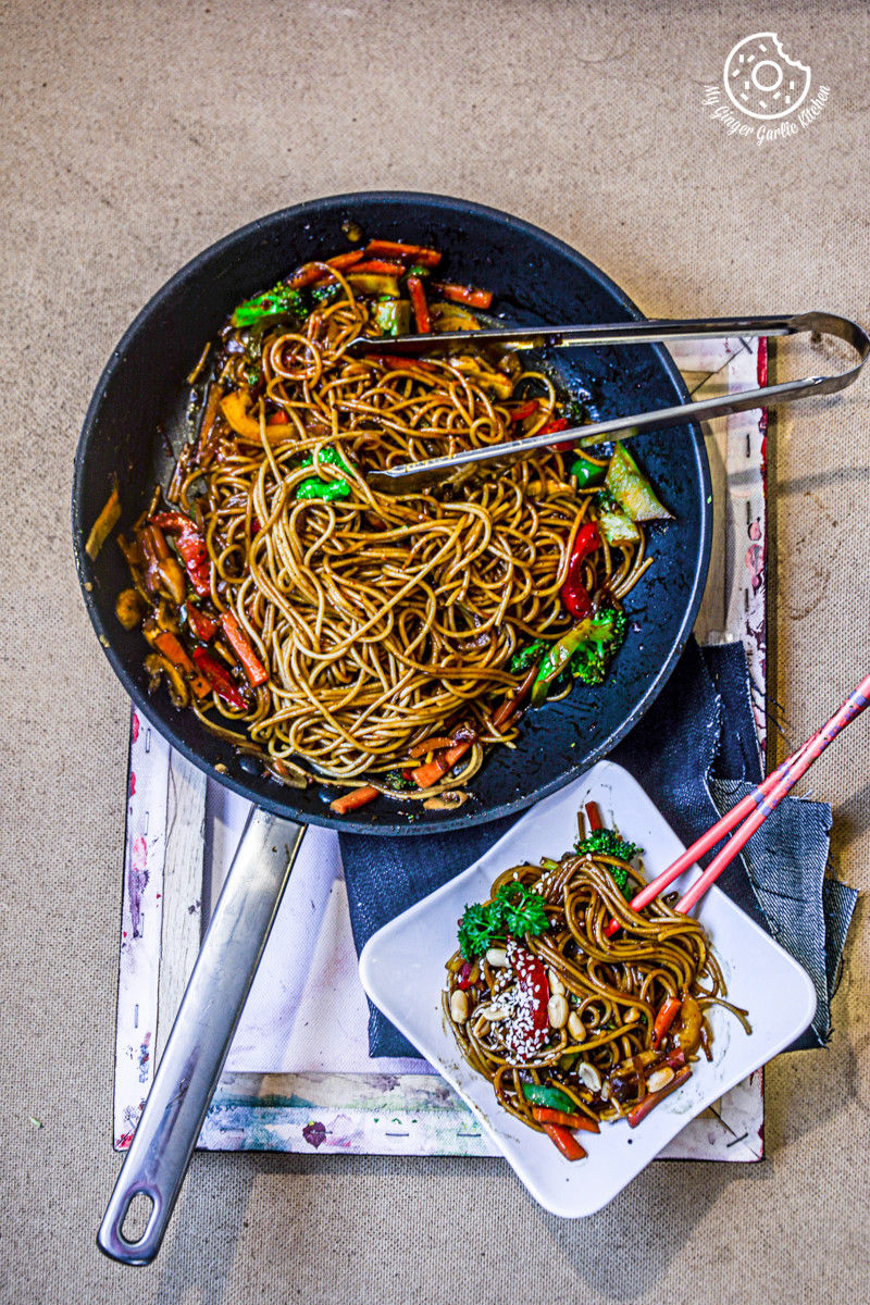 meal in a pan with chopsticks and a plate of vegetable teriyaki noodles