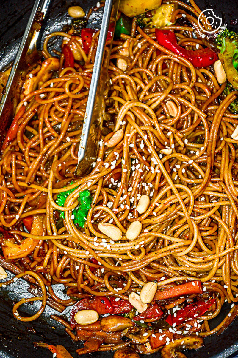 asian vegetable teriyaki noodles in a wok with chopsticks and vegetables