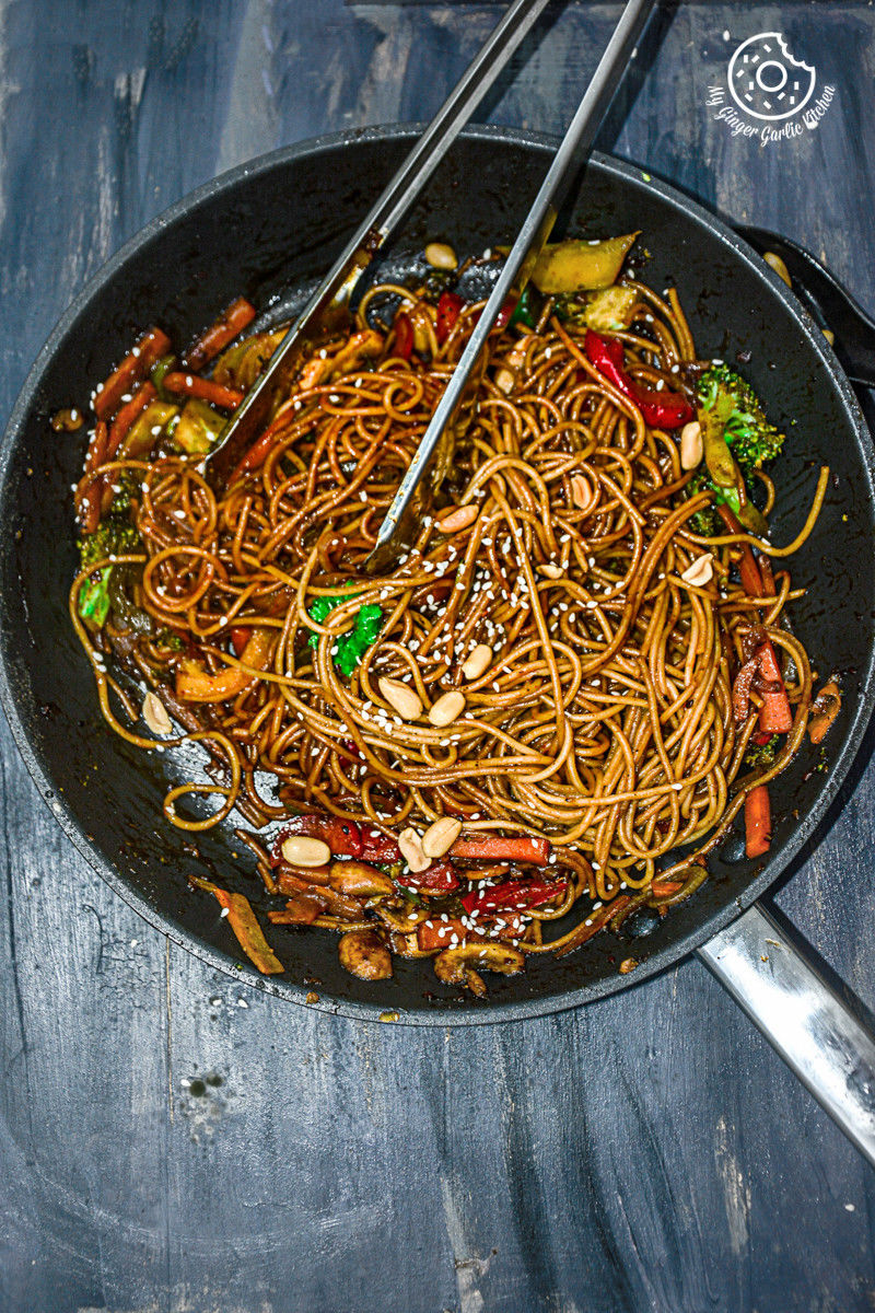 asian vegetable teriyaki noodles in a wok with chopsticks on a table