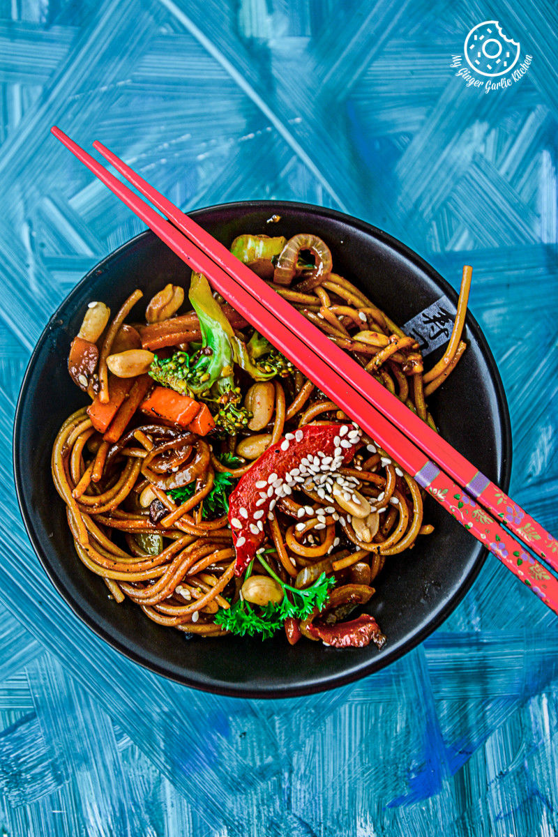 asian vegetable teriyaki noodles with vegetables and mushrooms in a black bowl