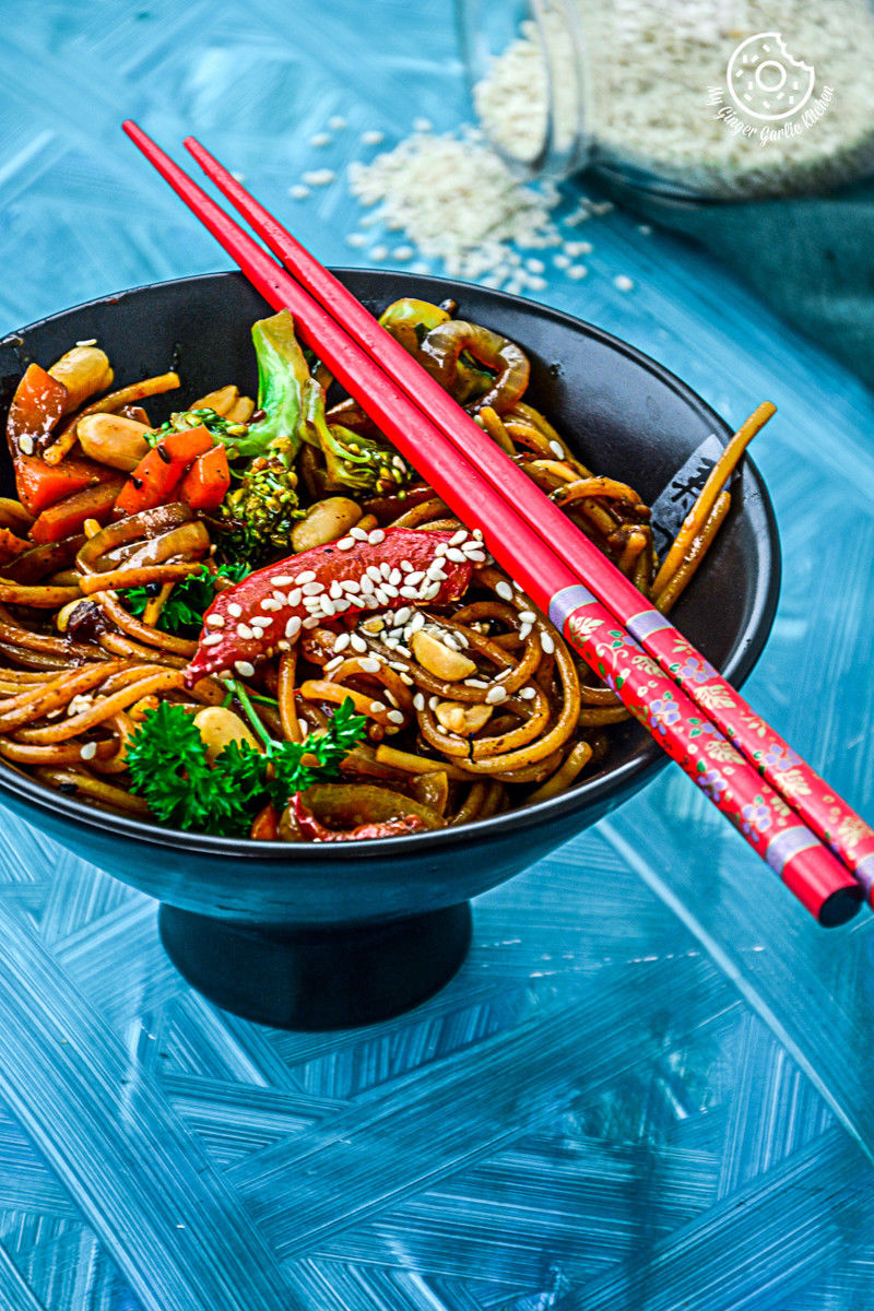 asian vegetable teriyaki noodles and vegetables in a bowl with chopsticks