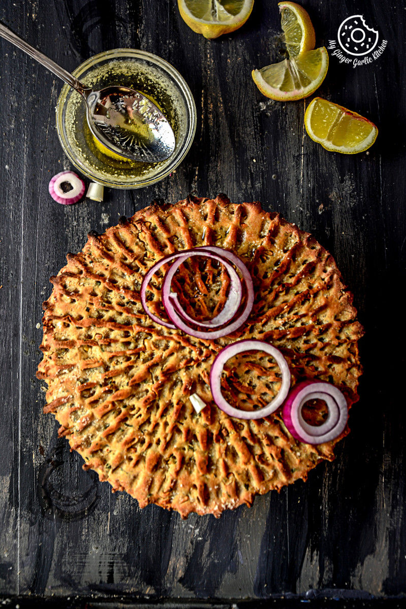 rajasthani khoba roti with a bowl of ghee, onion slices, and lemons on a table