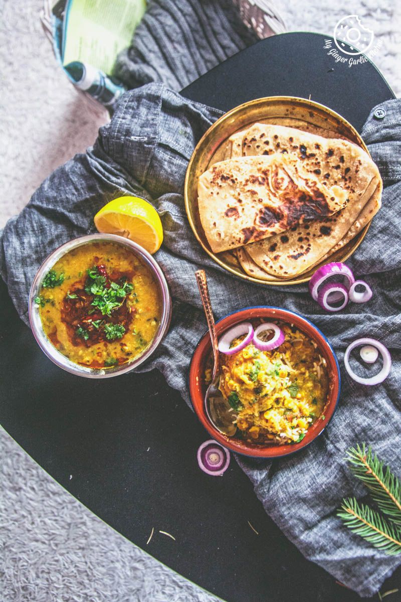 a bowl of restaurant style dal tadka with a bowl of dal rice and a plat of parathas on a table with a cloth