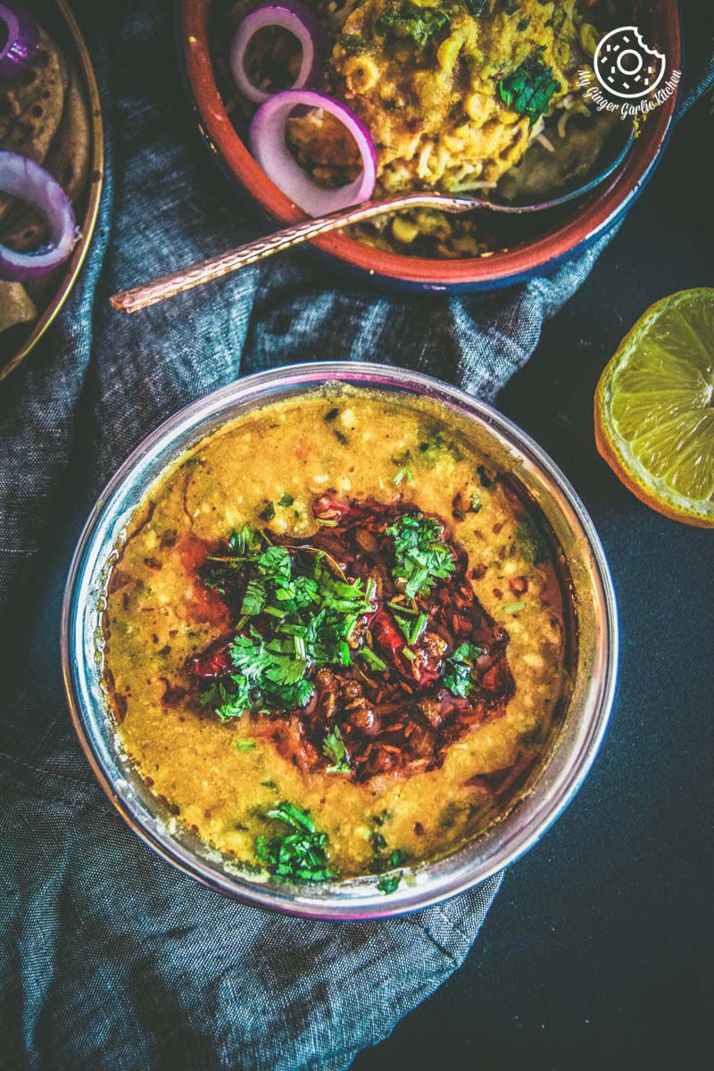 a close up of a bowl of restaurant style dal tadka with a bowl of dal rice and a lemon