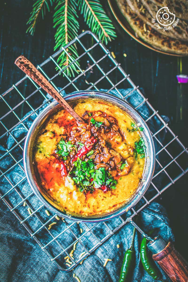 a close up of a bowl of restaurant style dal tadka with a spoon in it