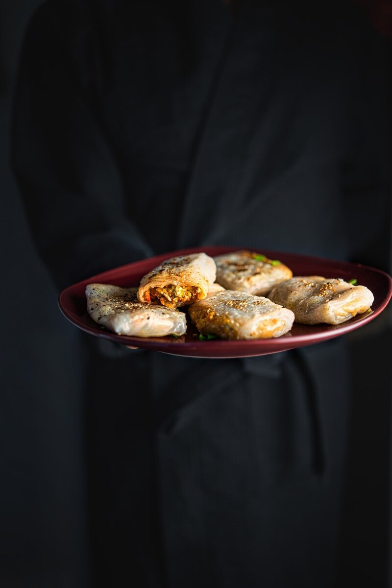 Serving plate of stuffed rice paper dumplings presented on a dark background, ideal for vegan party food or Asian-inspired meals