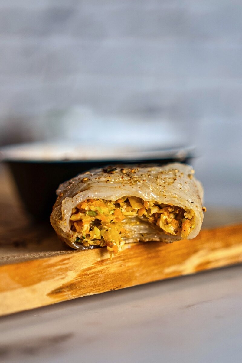 Close-up of a rice paper dumpling with savory vegetable and tofu filling, showcasing vegan Asian fusion cuisine