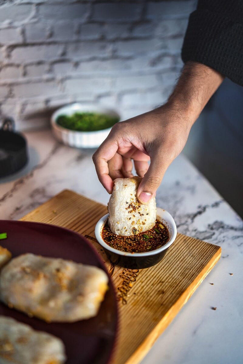 Hand dipping a rice paper dumpling into soy dipping sauce, delicious Asian street food appetizer idea