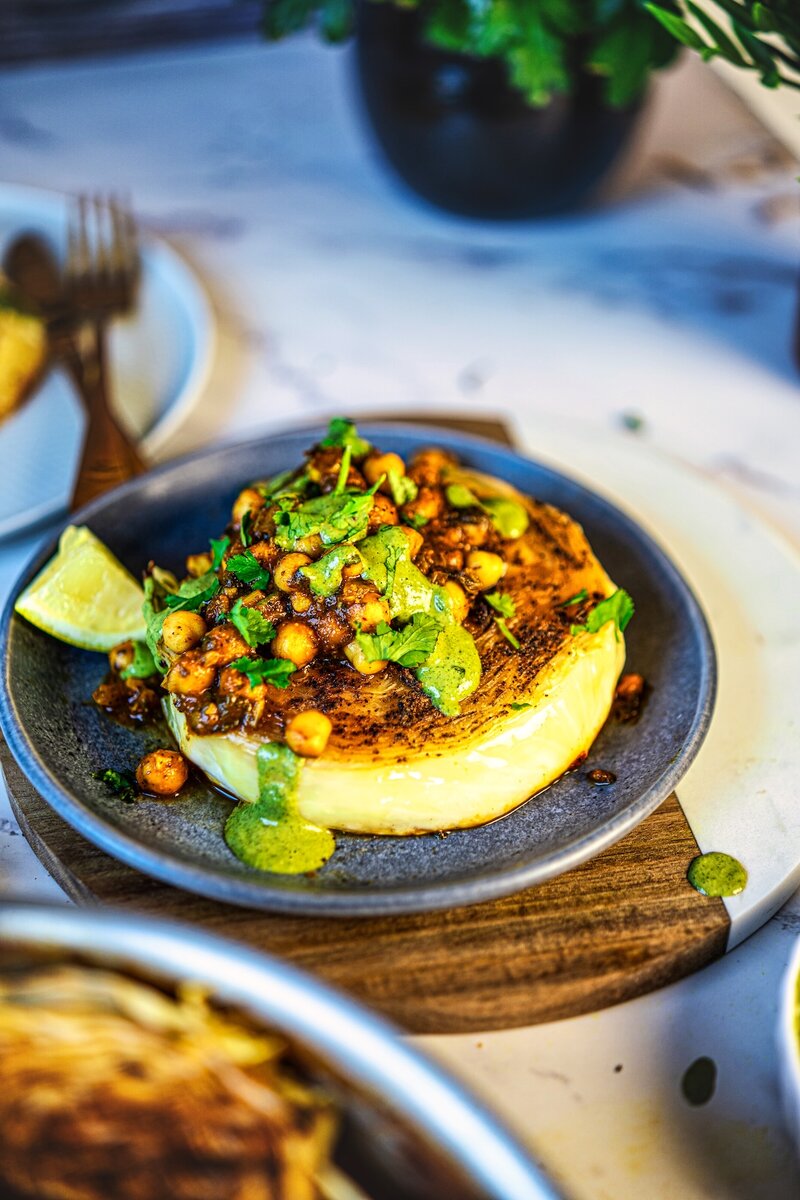 Roasted cabbage steaks plated with chickpeas and creamy cilantro tahini sauce for a vegan dinner