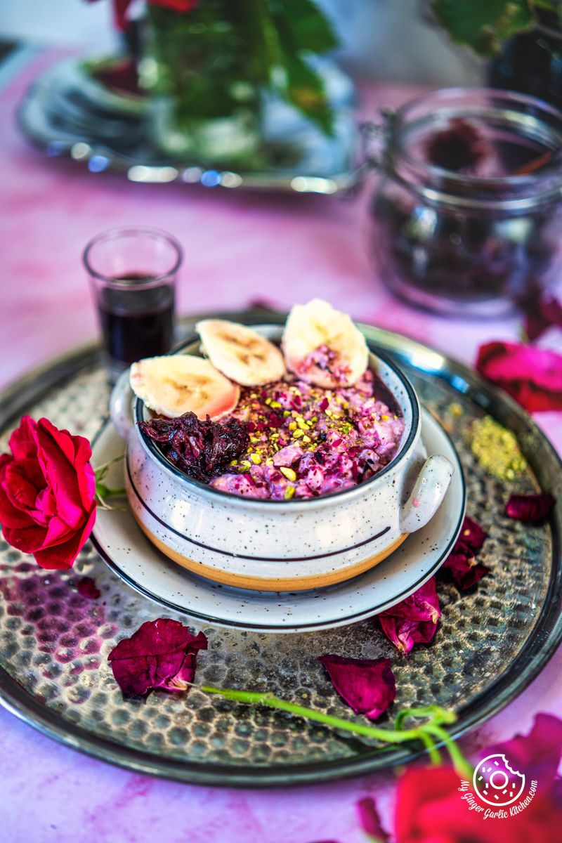a pink table topped with metal plate and bowl of rose overnight oats