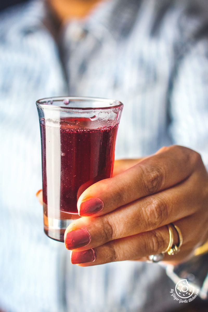a female holding homemade rose syrup small glass
