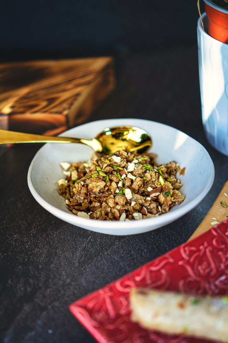 a plate of roti ka churma on a table with a golden spoon