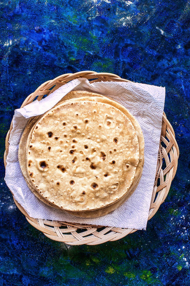 A top view of a basket containing rotis aka round unleavened Indian flatbreads made from whole wheat flour