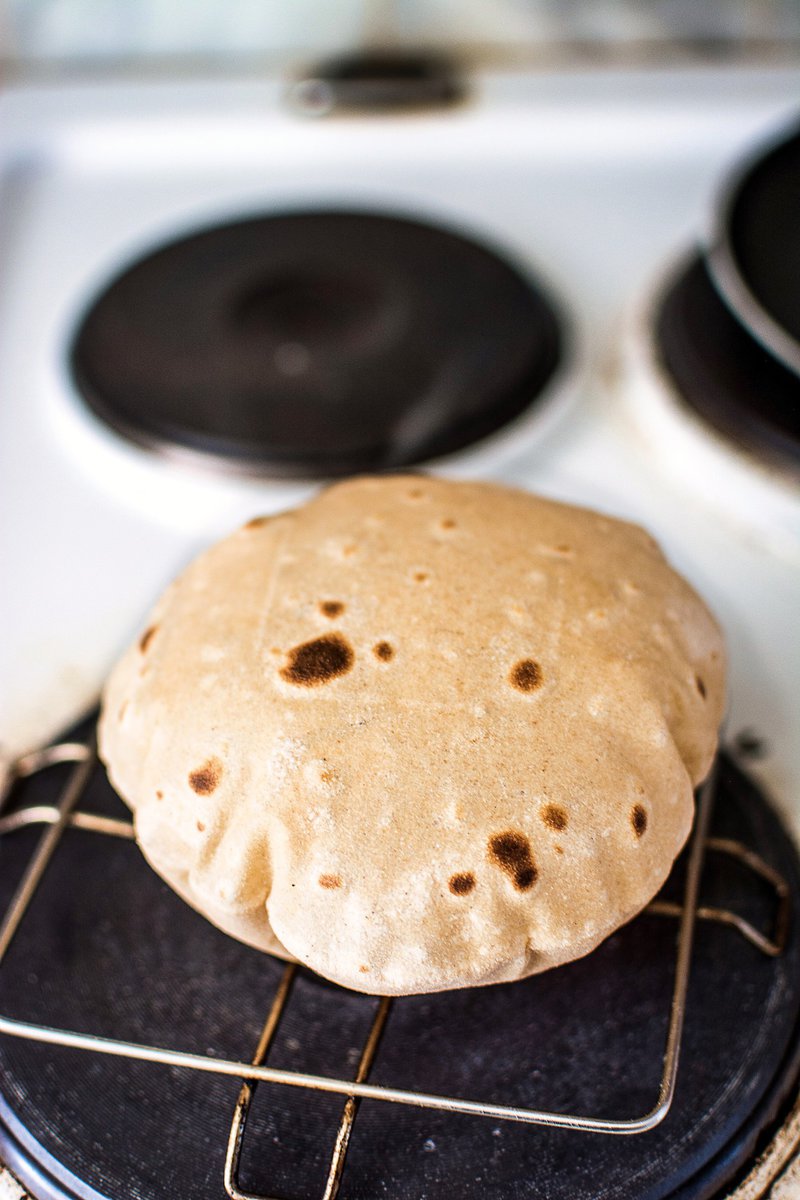 puffed roti on a stovetop grill above an open induction