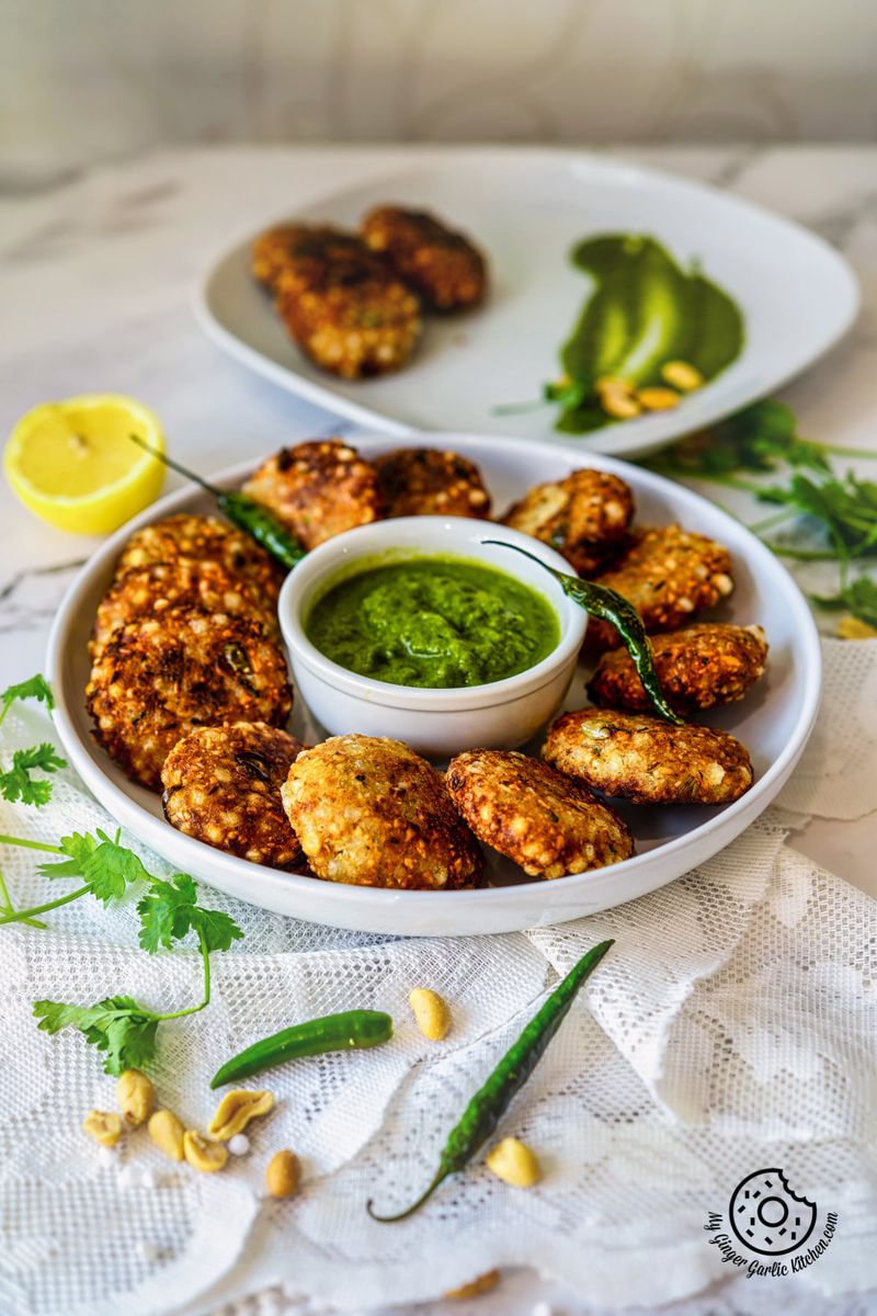 sabudana vada in a white plate with green chutney fried green chilies