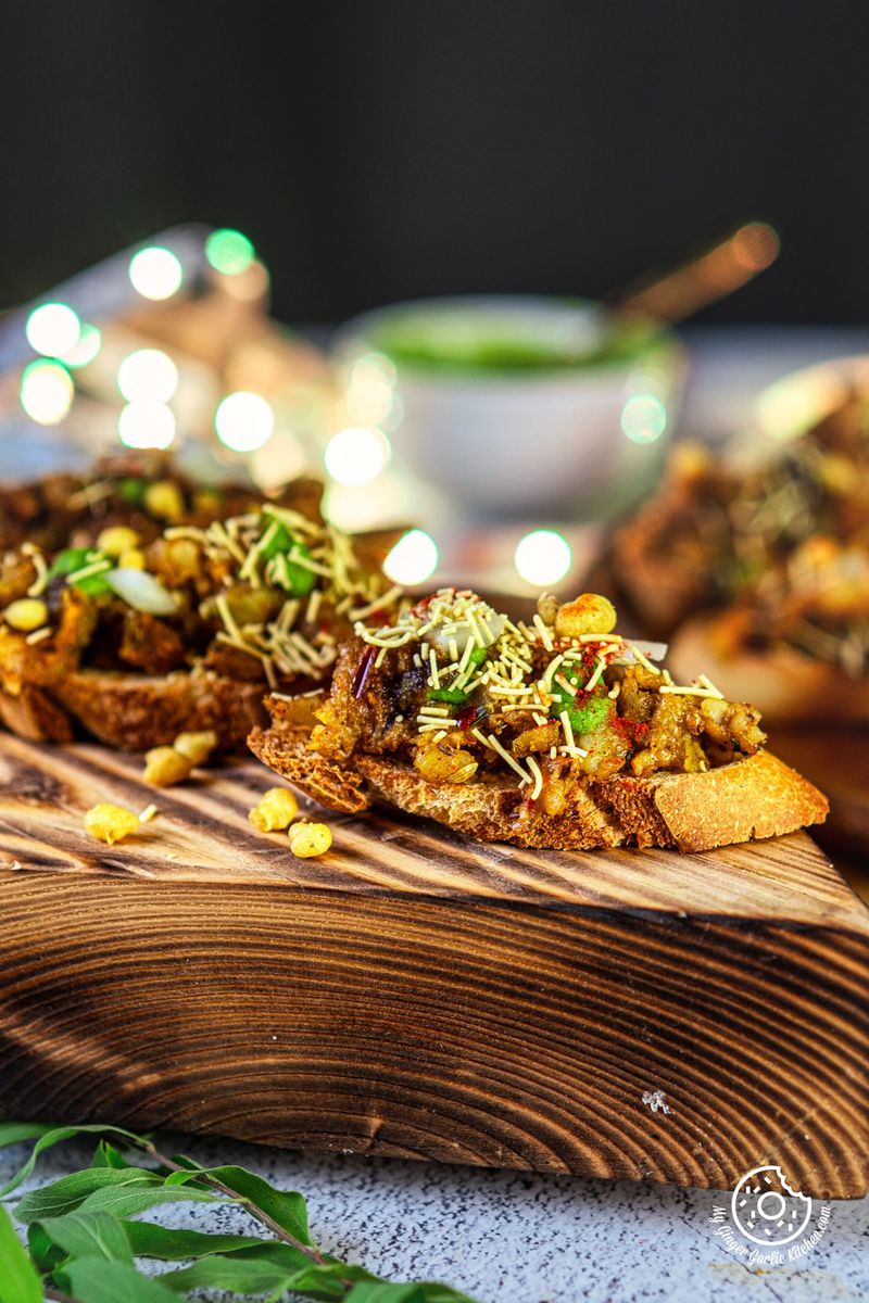 a wooden board with Samosa Chaat Bruschetta on it