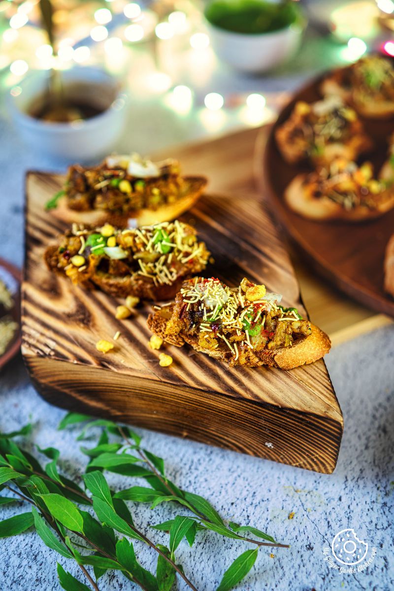there are 3 small Samosa Chaat Bruschetta on a wooden board
