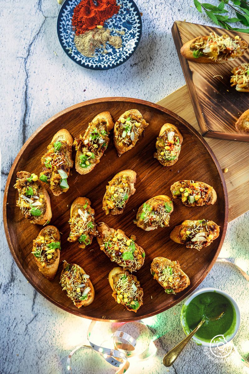 overhead photo of 15 of Samosa Chaat Bruschettas on a wooden plate on a table