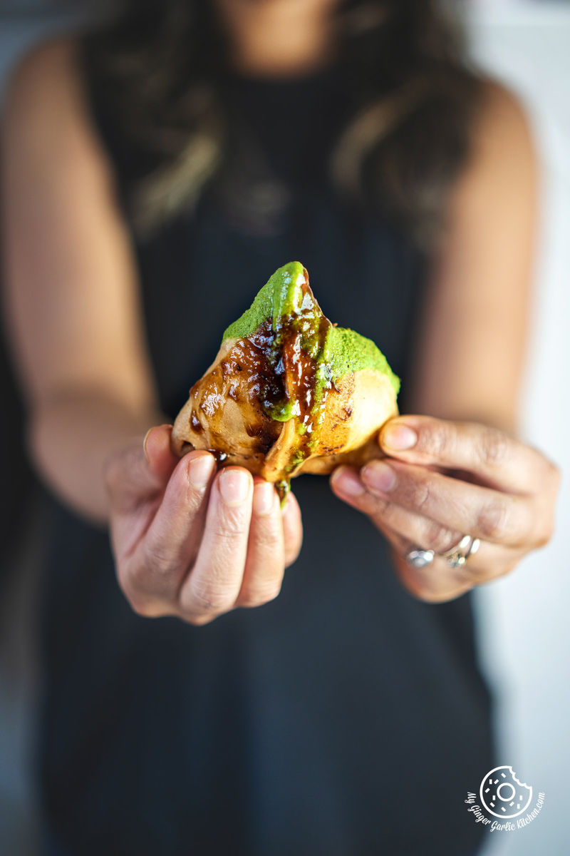 photo of a woman holding a piece of fried samosa in her hands
