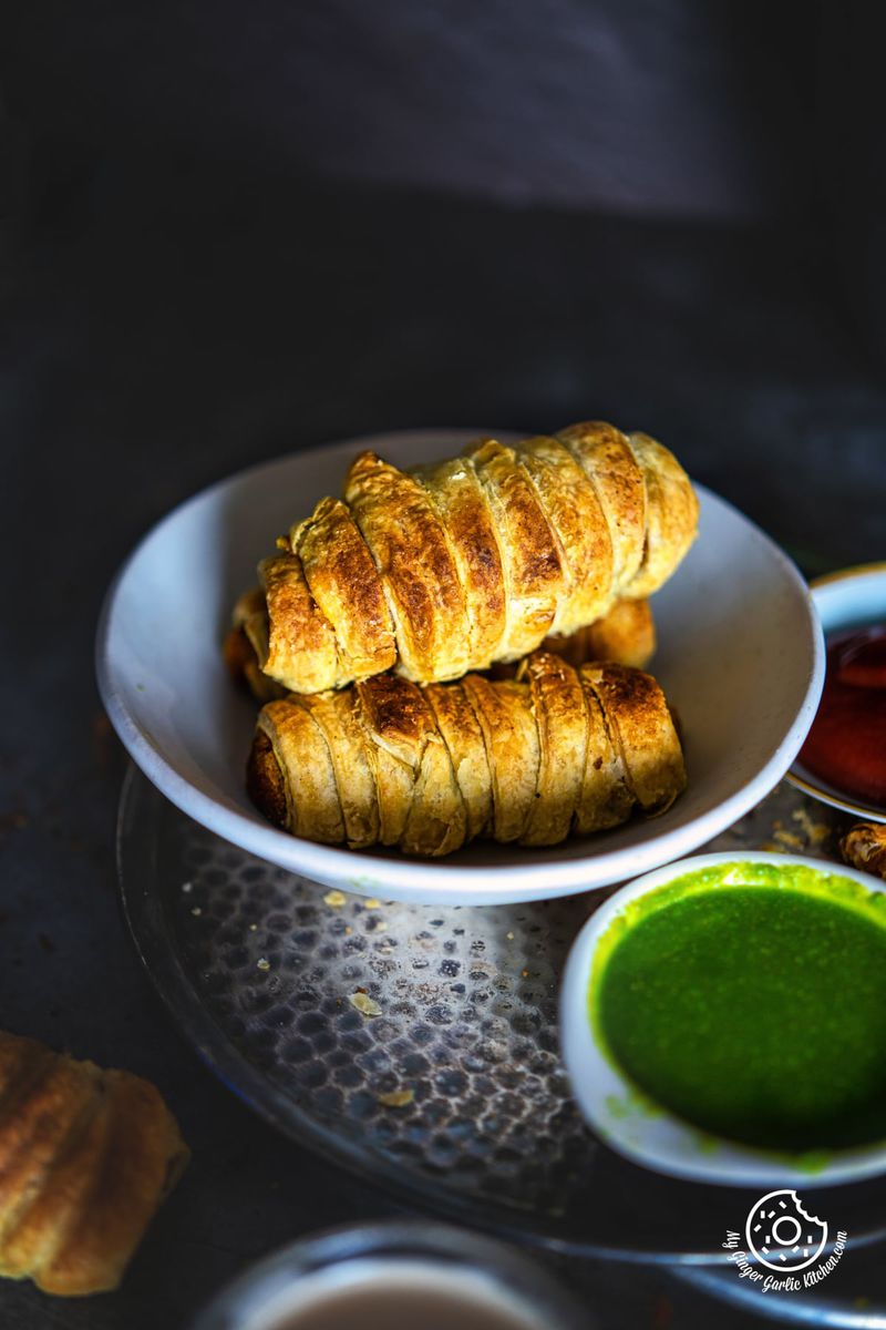 close up of a bowl of samosa roll with a green sauce on the side