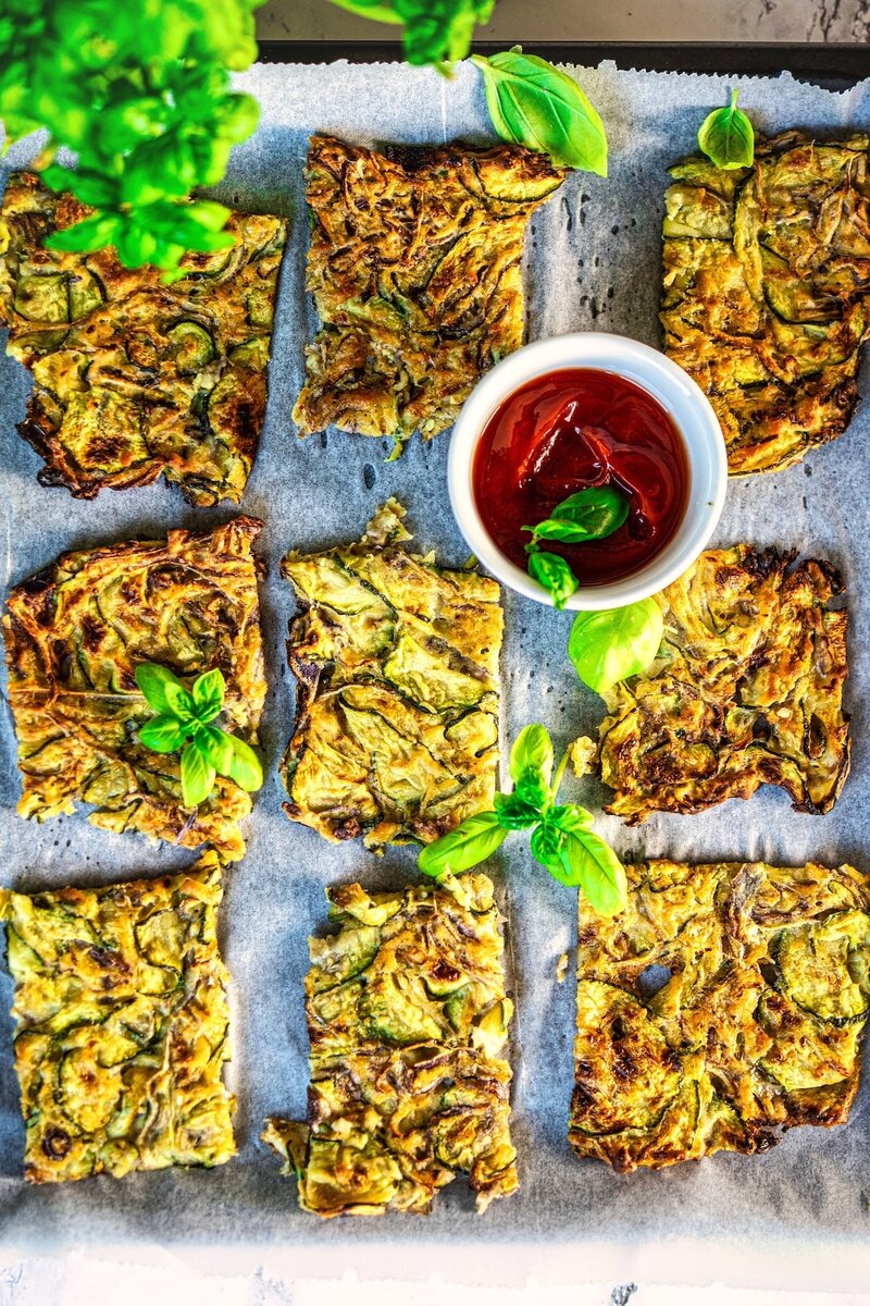 Nine slices of baked scarpaccia zucchini tart arranged with tomato sauce and basil garnish