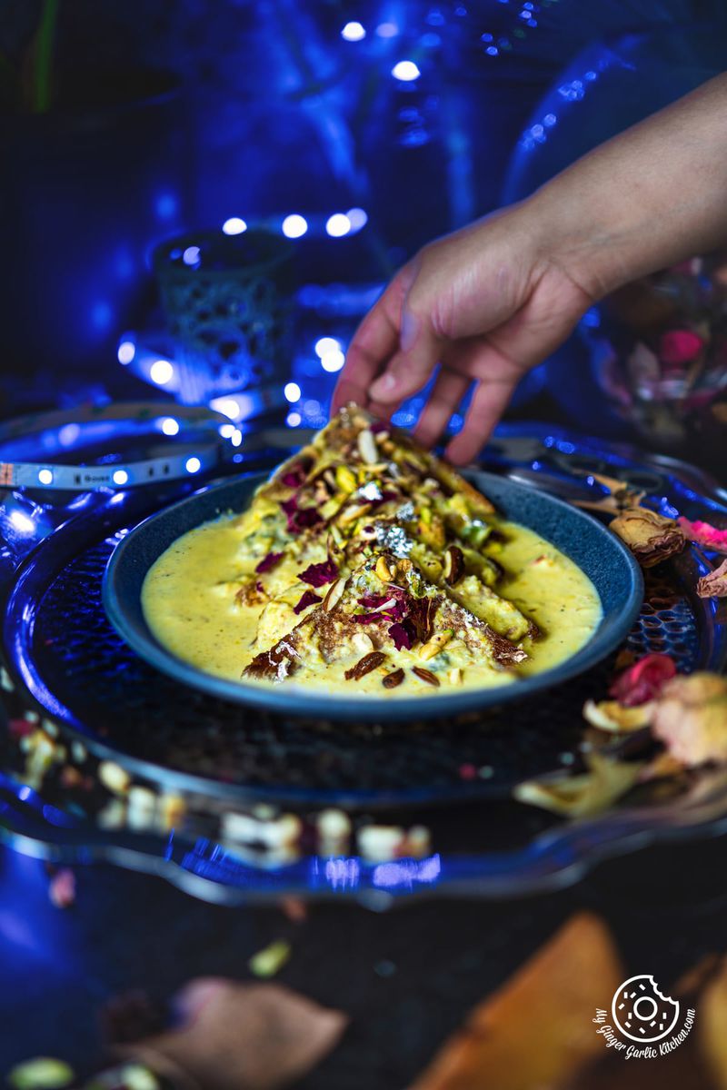 a hand is trying to hold shahi tukda or shahi tukra from the plate