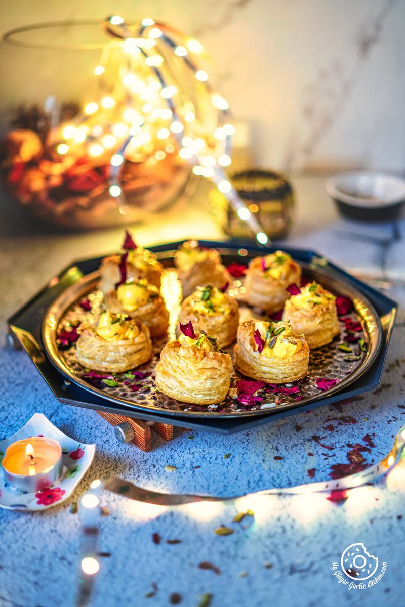 a tray of shrikhand puff pastry cups with a candle in the background