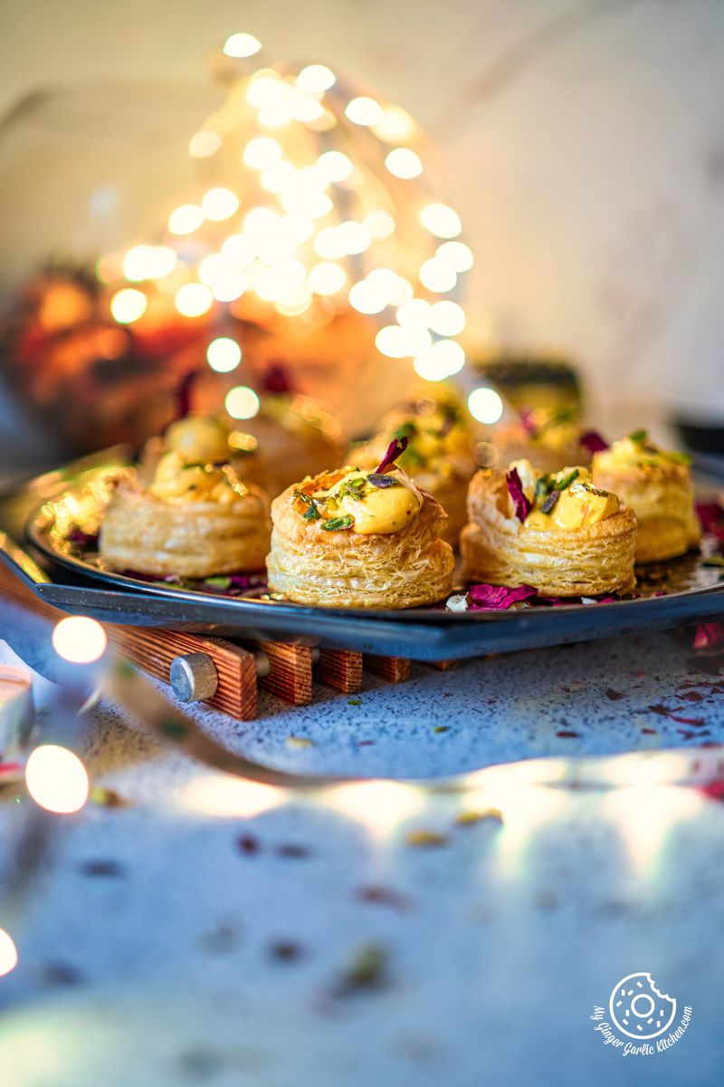 photo of a plate of shrikhand puff pastry cups with a lights in the background