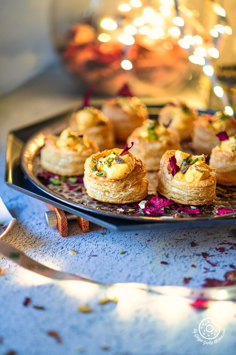 photo of a tray of shrikhand puff pastry cups with dried rose petals on a tables