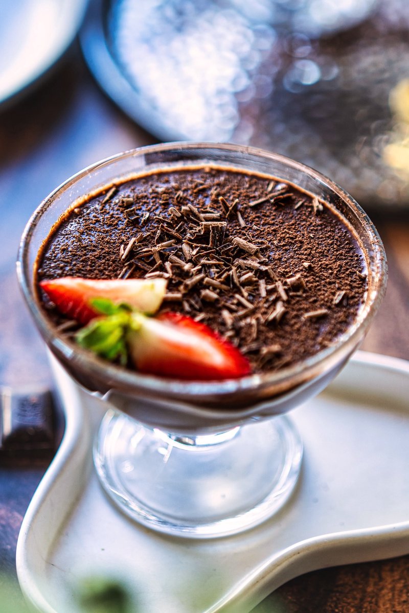 Creamy silken tofu chocolate pudding topped with cacao powder, shaved dark chocolate, and fresh strawberries in a glass dessert bowl