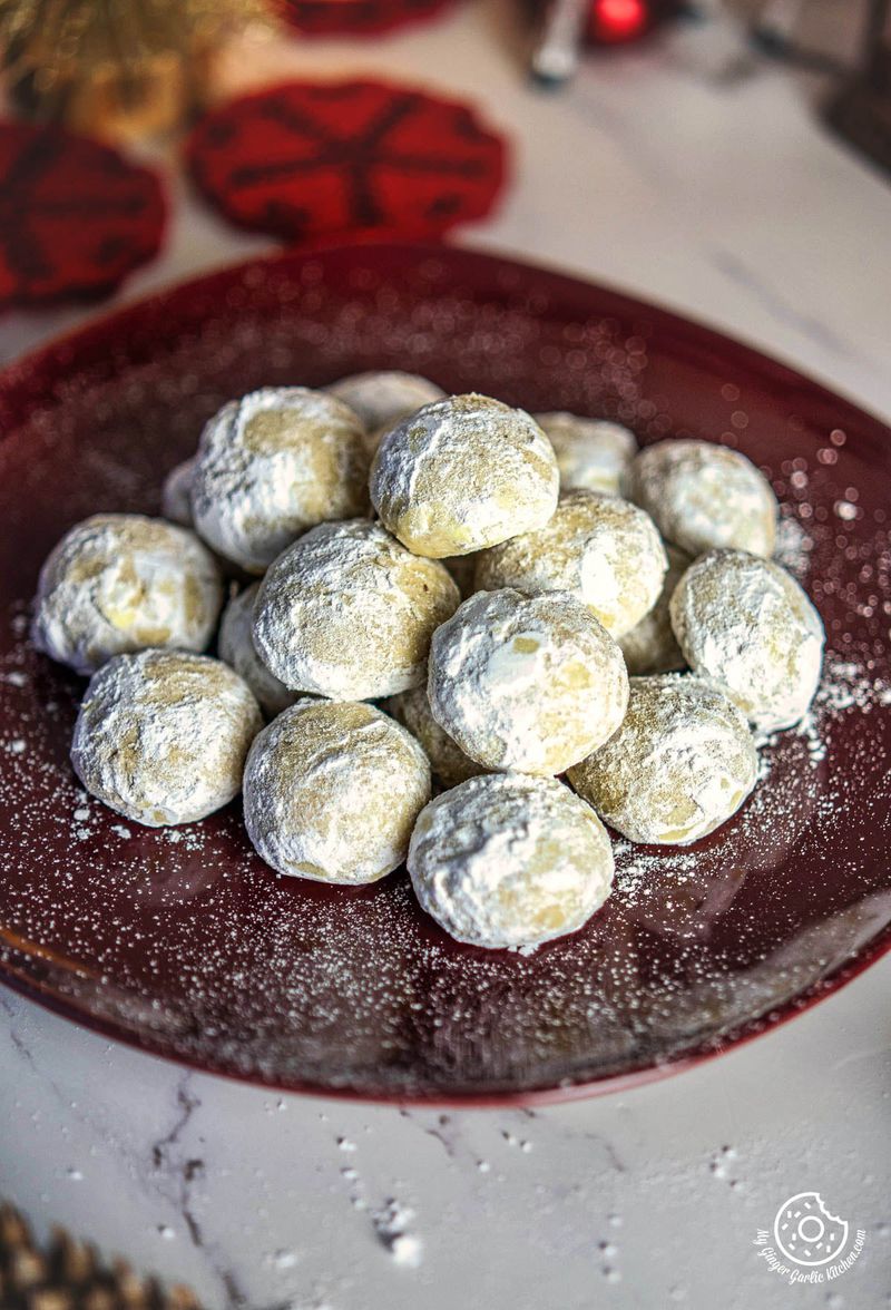 closeup shot of a plate full of sugar coated snowball cookies on a table