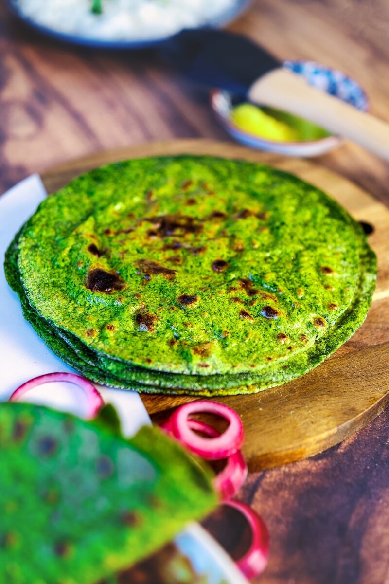 Stack of soft spinach rotis on a wooden board, healthy green palak roti for Indian meals