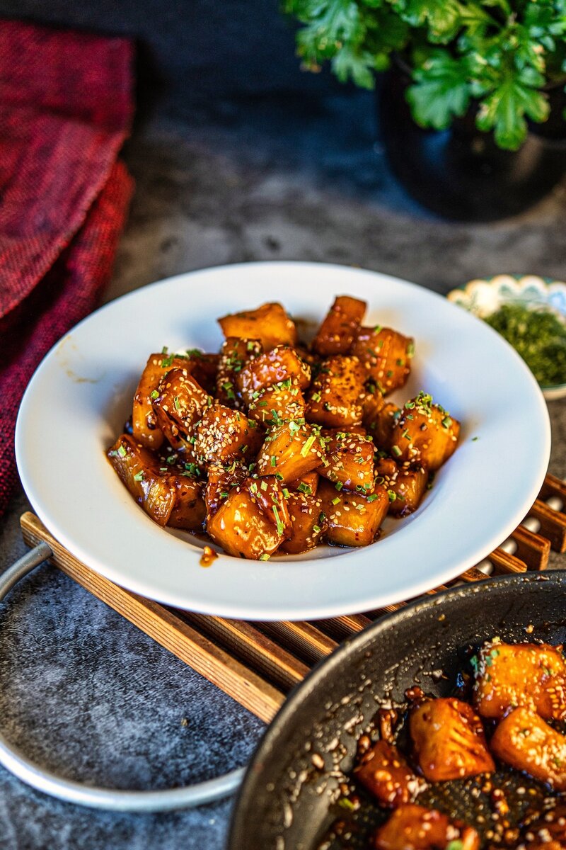 Sticky chili garlic pineapple bowl with rich glossy sauce, charred pineapple pieces, sesame seeds, and fresh chives