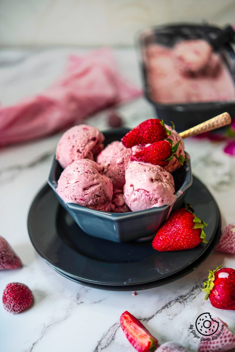 no churn strawberry ice cream in a grey bowl and some strawberries on side