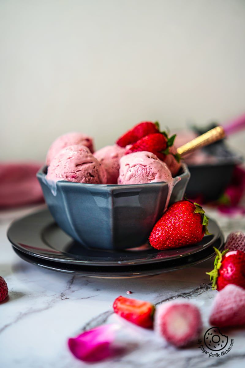 no churn strawberry ice cream in a grey bowl and some strawberries on side