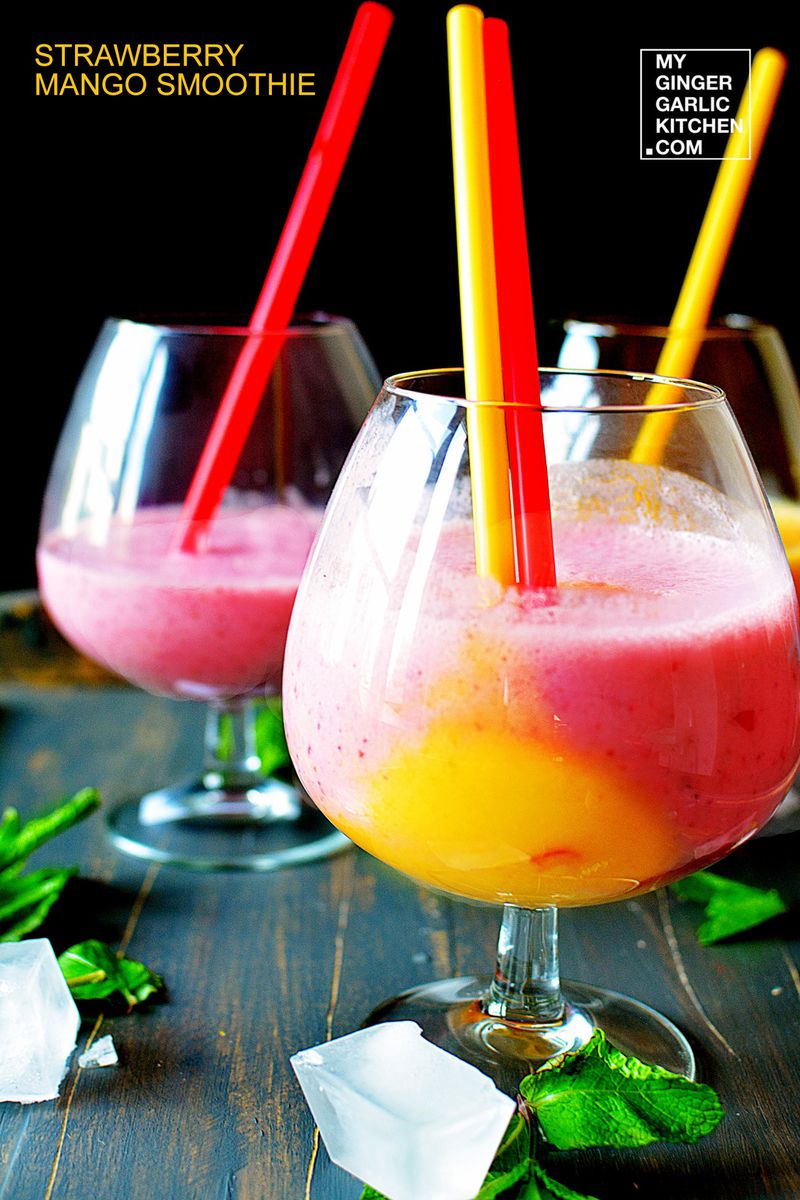 two glasses of strawberry mango milkshake with ice cubes and mint leaves